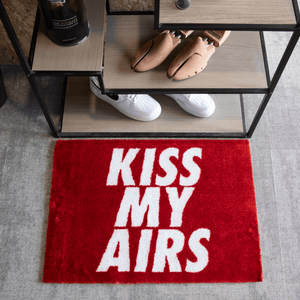 a red rug with white text on it and shoes on a shelf
