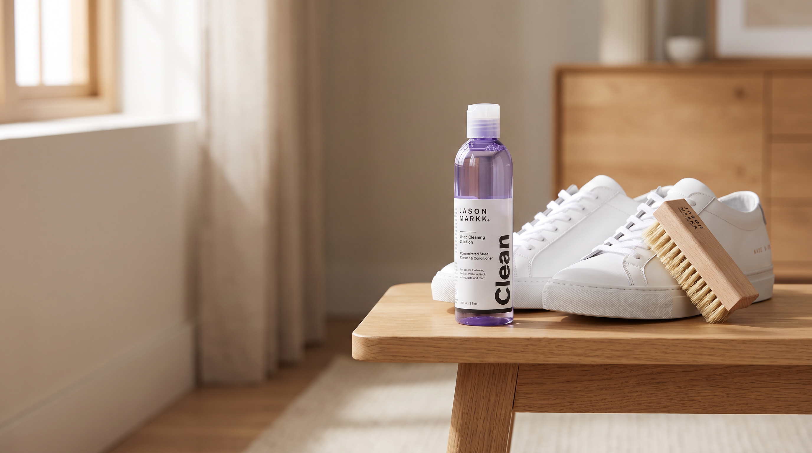 Fles Jason Markk Premium Deep Cleaner naast witte sneakers en een schoonmaakborstel op een houten ondergrond